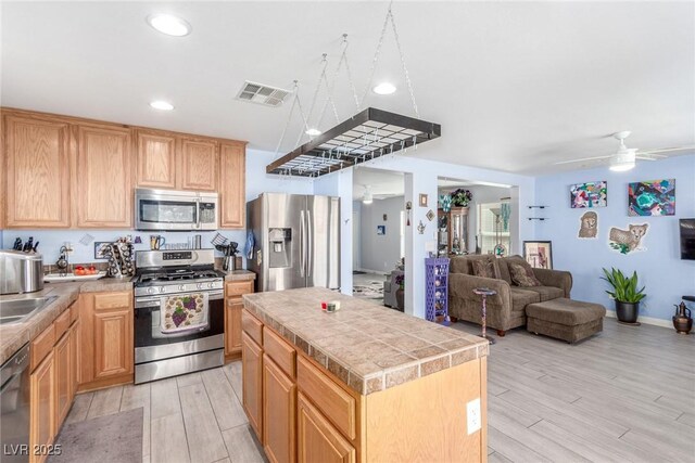 kitchen featuring open floor plan, ceiling fan, stainless steel appliances, light wood finished floors, and visible vents