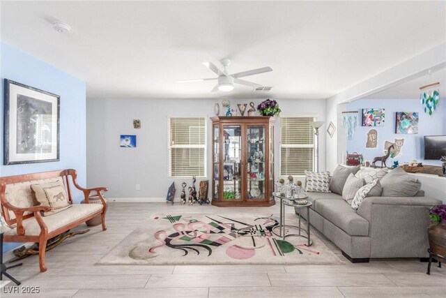 living room with ceiling fan, baseboards, wood finished floors, and visible vents