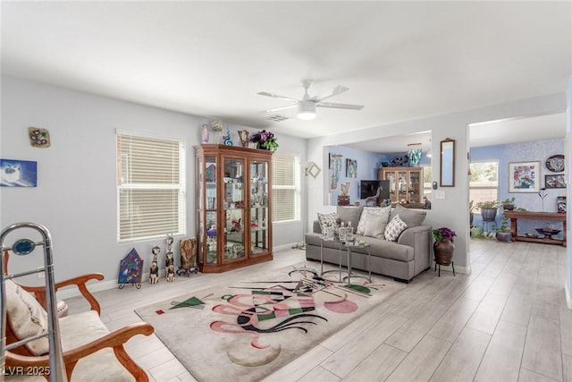 living room featuring light wood-style flooring, a healthy amount of sunlight, a ceiling fan, and visible vents