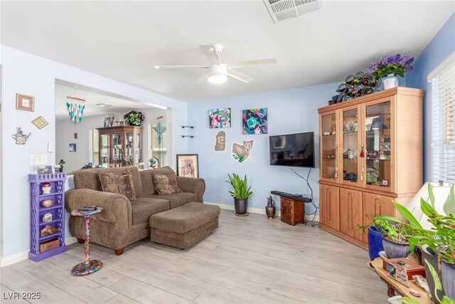 living room featuring light wood-style floors, visible vents, baseboards, and ceiling fan