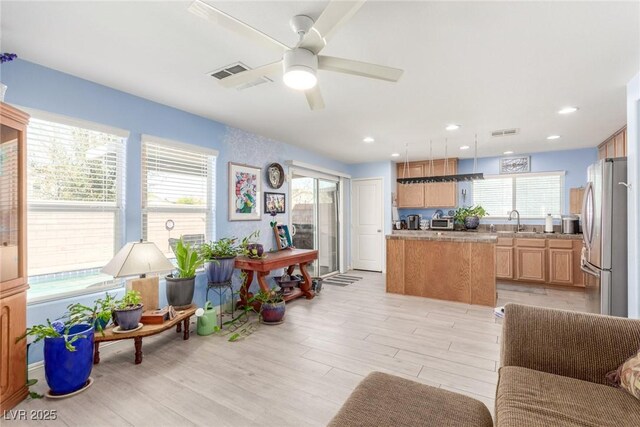 living area with light wood-style flooring, visible vents, recessed lighting, and ceiling fan