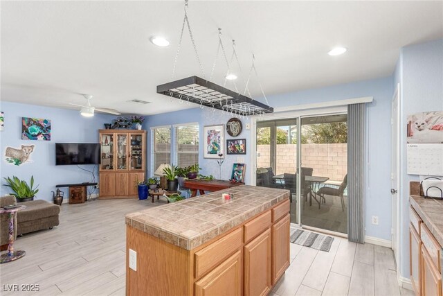 kitchen with ceiling fan, a wealth of natural light, open floor plan, and tile counters