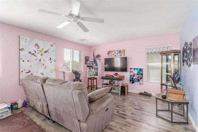 living area with light wood-style floors, visible vents, baseboards, and ceiling fan