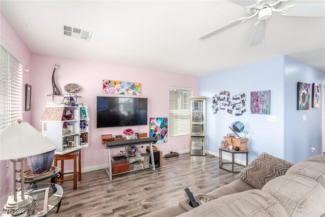 living room featuring wood finished floors, visible vents, a ceiling fan, and baseboards