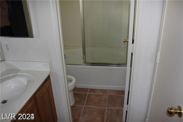 full bath with combined bath / shower with glass door, toilet, vanity, and tile patterned floors