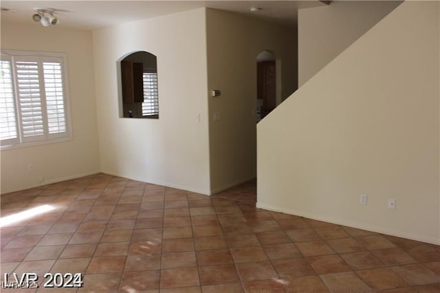 spare room with arched walkways and tile patterned floors