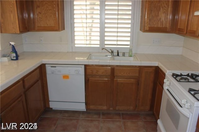 kitchen with brown cabinets, a sink, and white appliances