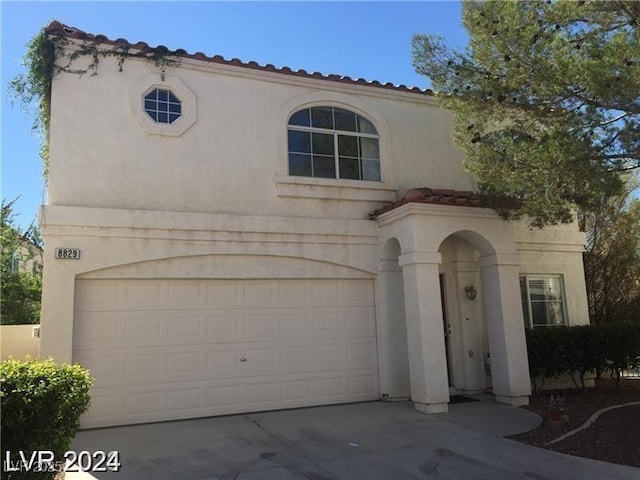 mediterranean / spanish house with a garage, driveway, and stucco siding
