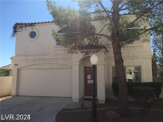 mediterranean / spanish home featuring stucco siding, an attached garage, and concrete driveway