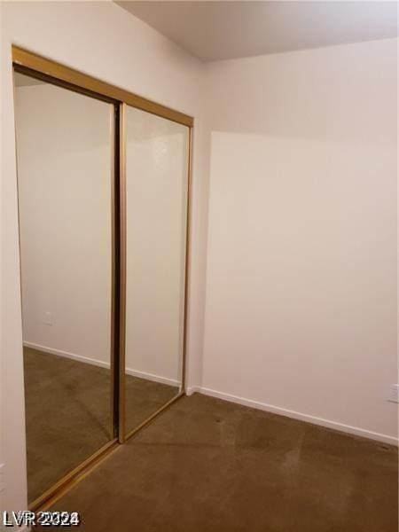 unfurnished bedroom with baseboards, carpet, and a closet