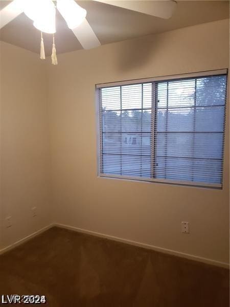 spare room featuring a ceiling fan, baseboards, and dark carpet