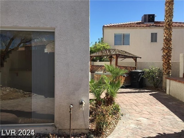 view of side of home featuring a pergola, a tiled roof, central air condition unit, stucco siding, and a patio area