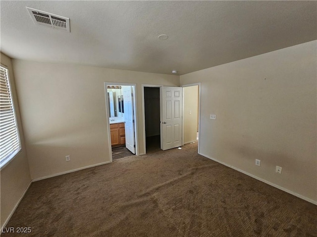 unfurnished bedroom with baseboards, dark colored carpet, visible vents, and multiple windows