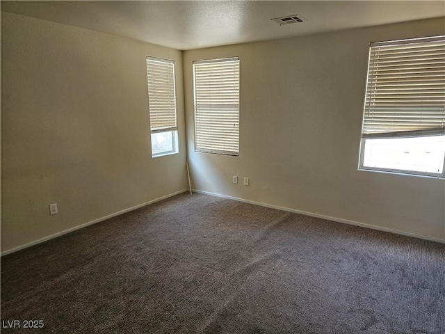 empty room with baseboards, carpet floors, visible vents, and a wealth of natural light
