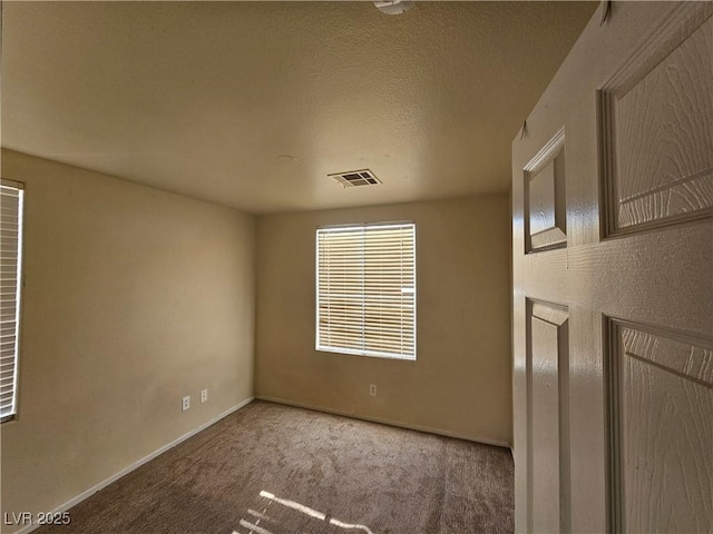 spare room with baseboards, visible vents, and carpet