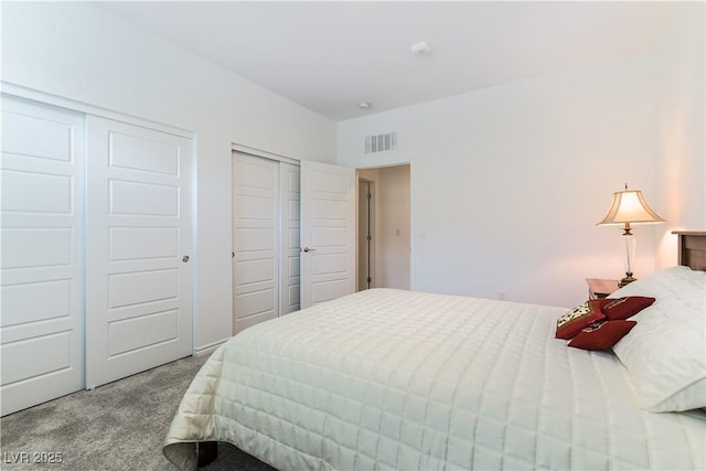 bedroom with carpet floors, multiple closets, and visible vents