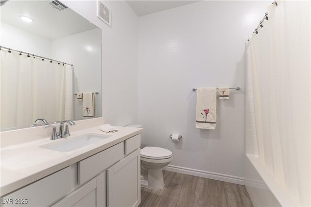 bathroom with toilet, wood finished floors, visible vents, and baseboards