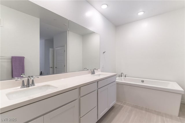 full bathroom featuring a garden tub, a sink, recessed lighting, and double vanity