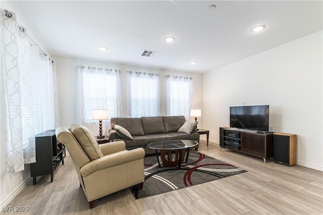 living area with baseboards, wood finished floors, visible vents, and a wealth of natural light