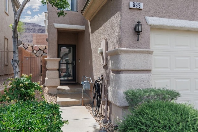 view of exterior entry featuring stucco siding and a garage