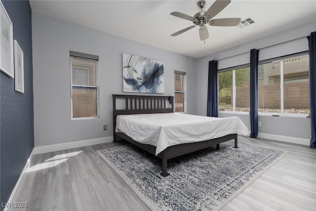 bedroom with ceiling fan, baseboards, wood finished floors, and visible vents