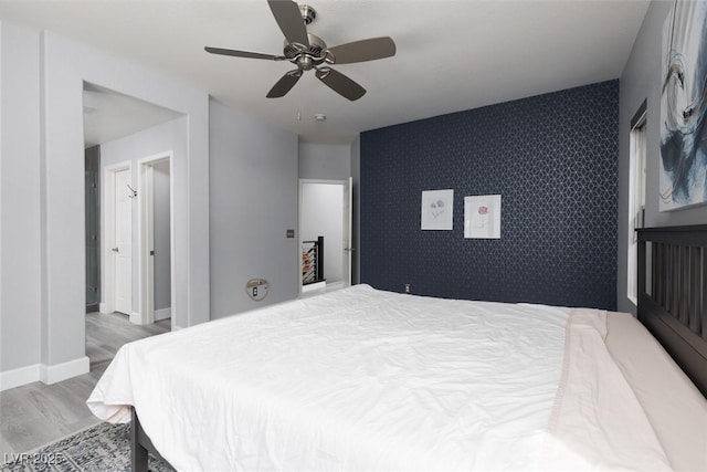 689 Principle Point Ave, Henderson, NV 89012 - bedroom featuring an accent wall, wood finished floors, wallpapered walls, a ceiling fan, and baseboards