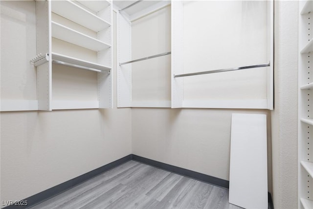 walk in closet with wood finished floors
