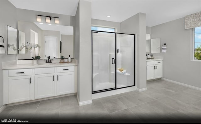 bathroom with tile patterned flooring, a sink, baseboards, two vanities, and a stall shower