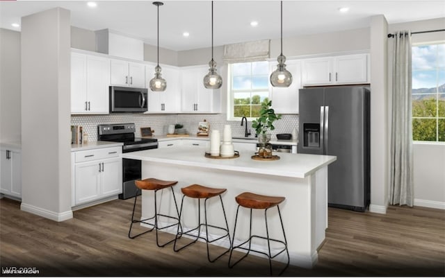 kitchen featuring a kitchen bar, appliances with stainless steel finishes, dark wood-type flooring, and white cabinetry