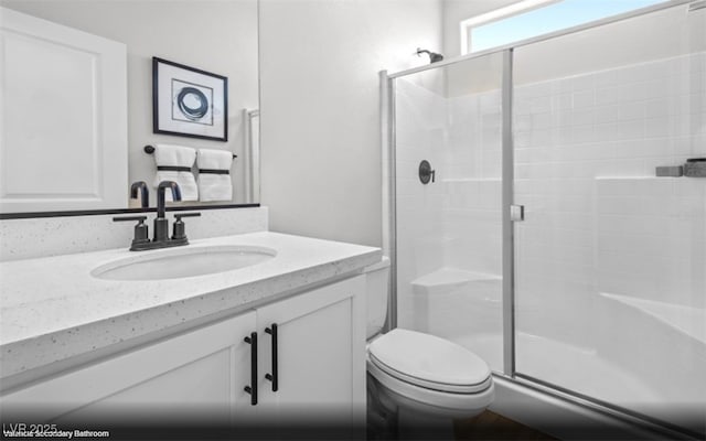 full bathroom featuring a shower stall, toilet, and vanity