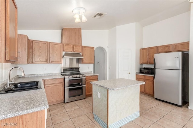 kitchen with a sink, stainless steel appliances, light countertops, under cabinet range hood, and visible vents