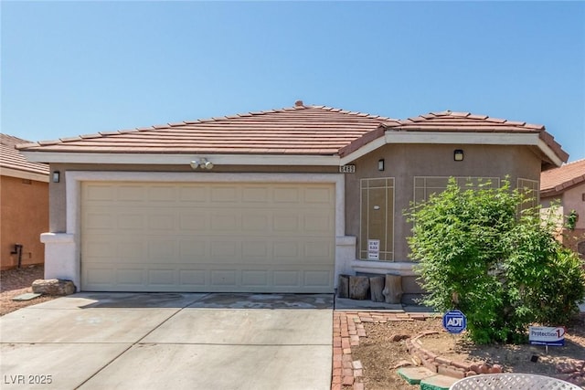 view of front of property featuring concrete driveway, a tile roof, stucco siding, and a garage