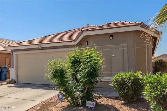 view of side of home with an attached garage, a tiled roof, driveway, and stucco siding