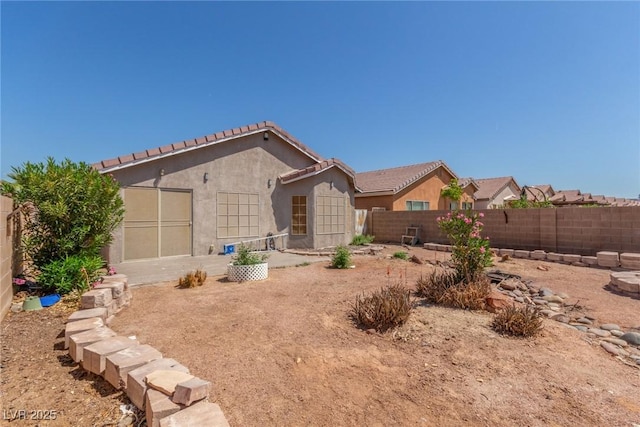 rear view of property with a tile roof, a fenced backyard, and stucco siding