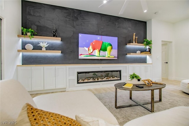 10709 Hunters Woods Pl, Las Vegas, NV 89134 - living area featuring an accent wall, a glass covered fireplace, wood finished floors, and baseboards