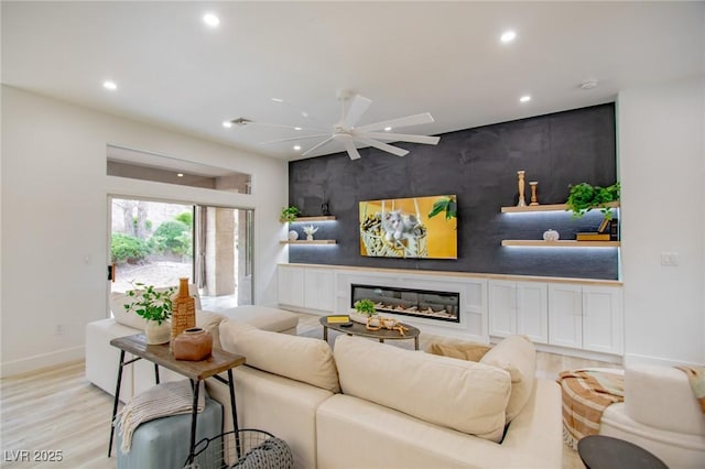 10709 Hunters Woods Pl, Las Vegas, NV 89134 - living room featuring an accent wall, recessed lighting, wood finished floors, a glass covered fireplace, and ceiling fan
