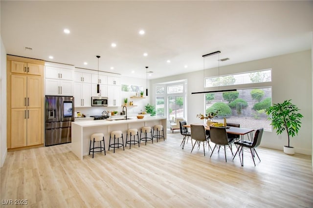 10709 Hunters Woods Pl, Las Vegas, NV 89134 - kitchen featuring appliances with stainless steel finishes, a breakfast bar area, an island with sink, light wood-type flooring, and recessed lighting