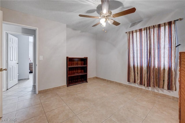 empty room featuring light tile patterned floors, ceiling fan, and baseboards