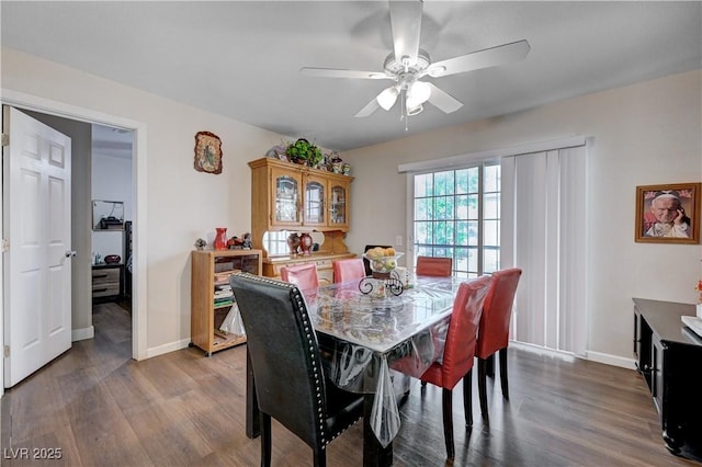 dining area featuring a ceiling fan, dark wood-style floors, and baseboards