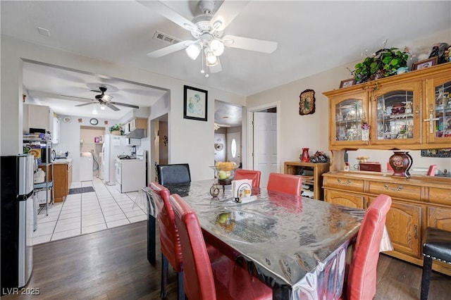 dining area featuring dark wood-style flooring, ceiling fan, washer and dryer, and visible vents