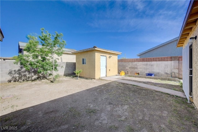 rear view of property featuring an outdoor structure, a patio, stucco siding, and a fenced backyard