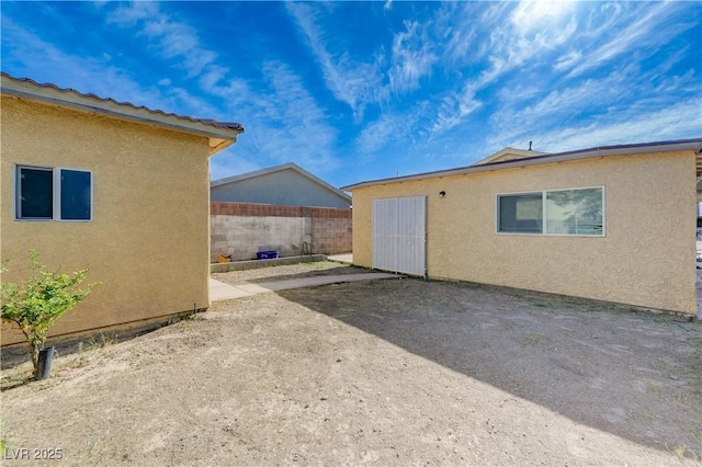exterior space with stucco siding, fence, and a patio area