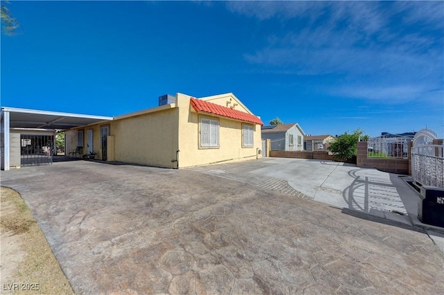 exterior space with stucco siding, a tiled roof, and fence