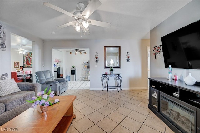 living area featuring light tile patterned flooring, a ceiling fan, and baseboards