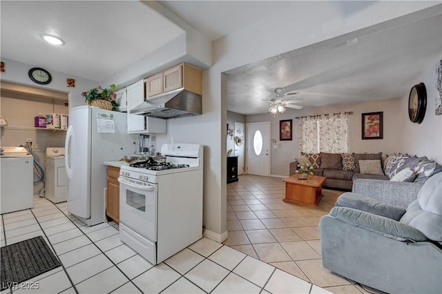 kitchen with white appliances, light tile patterned floors, washer and dryer, under cabinet range hood, and open floor plan