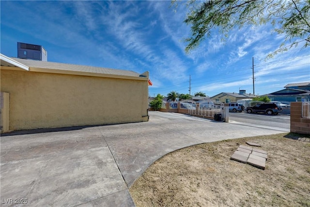 view of home's exterior featuring fence, stucco siding, a residential view, and a patio area
