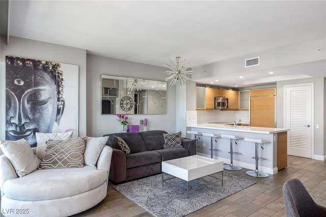 living area featuring an inviting chandelier, visible vents, light wood-type flooring, and baseboards