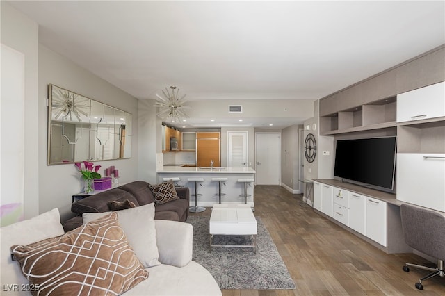living area with an inviting chandelier, wood finished floors, and visible vents