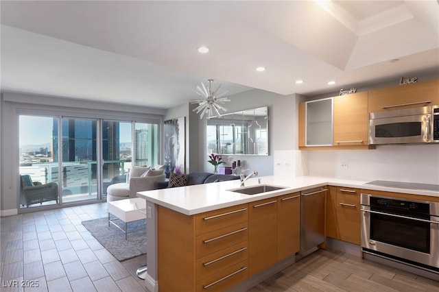 kitchen with a sink, appliances with stainless steel finishes, light countertops, open floor plan, and recessed lighting