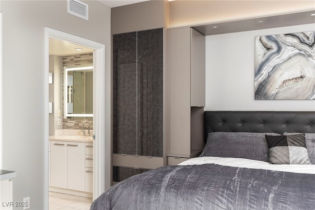 bedroom featuring visible vents, ensuite bath, and a sink
